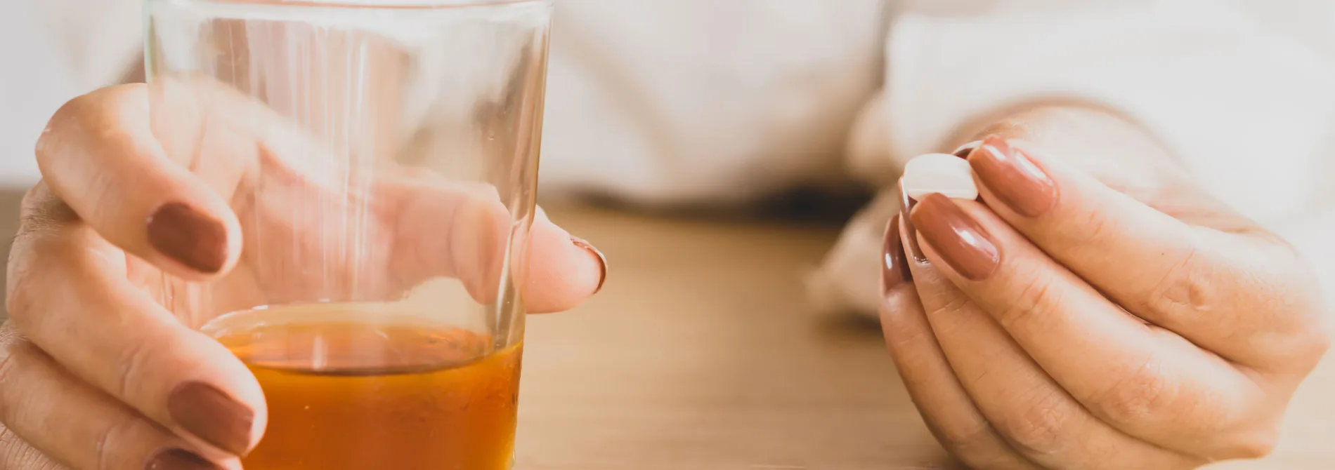 woman with drink and pill in hands