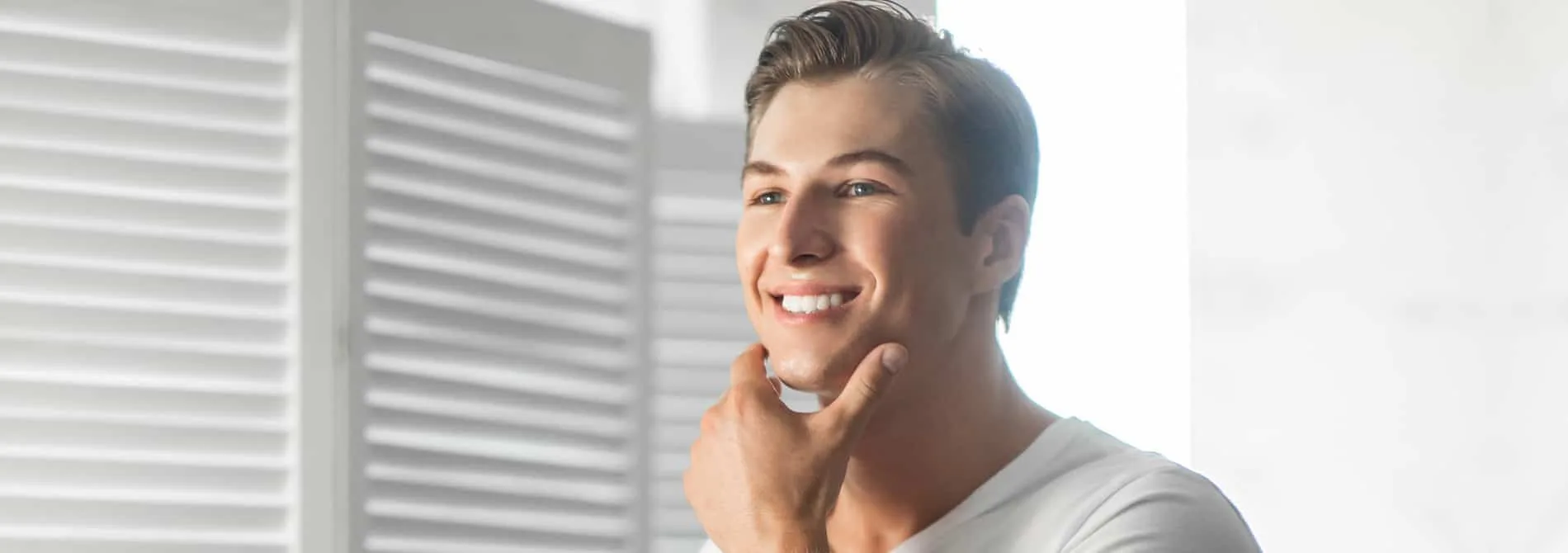 Man looking in mirror with hand on face