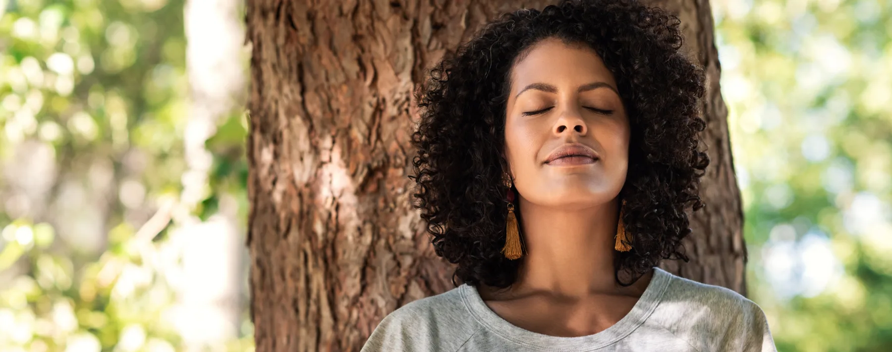 calm woman leaning against a tree