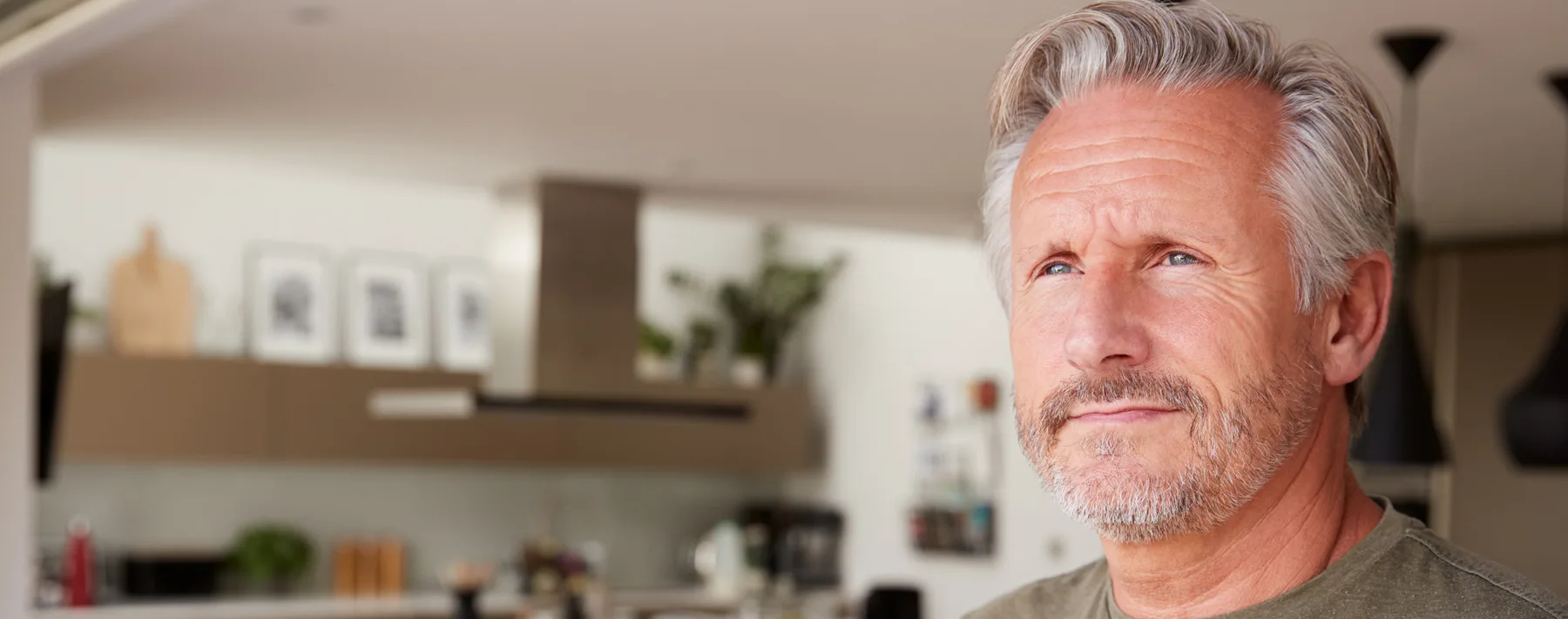 Senior Man Standing And Looking Out Of Kitchen Door Drinking Coffee