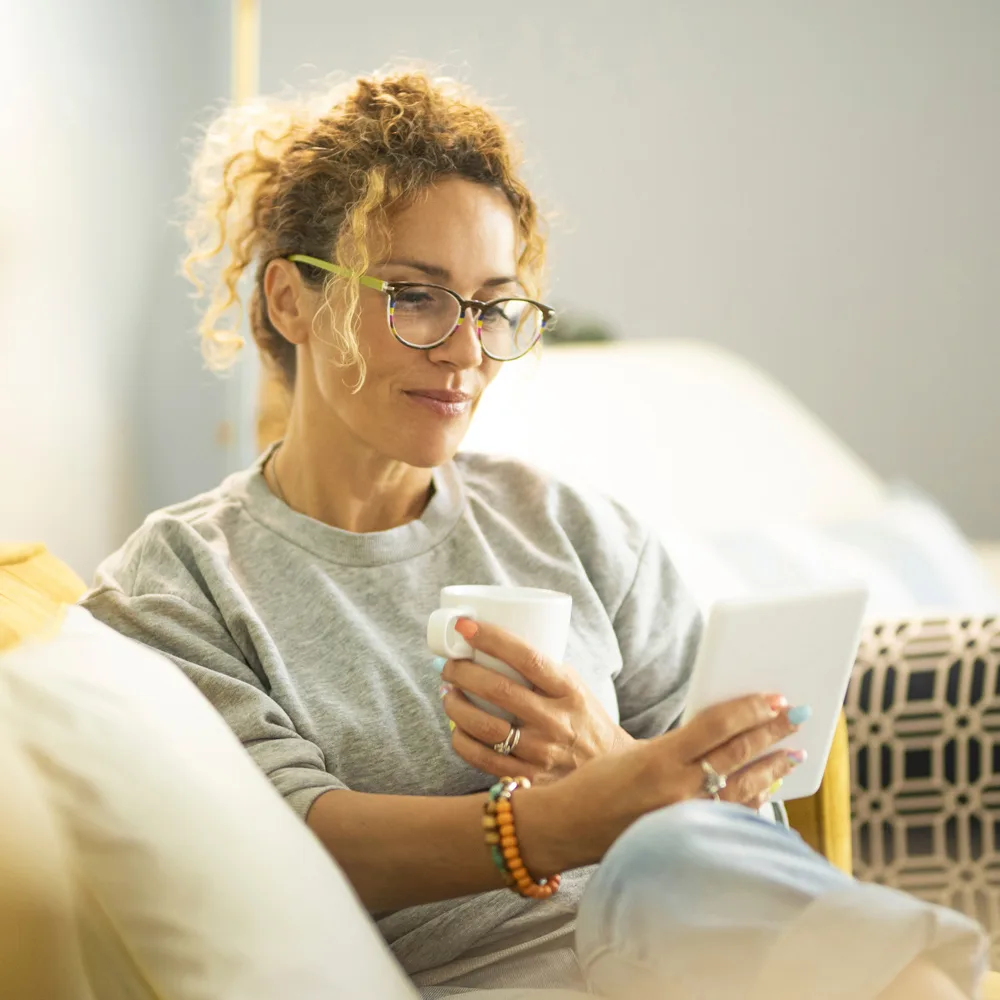 Woman drinking coffee reading tablet