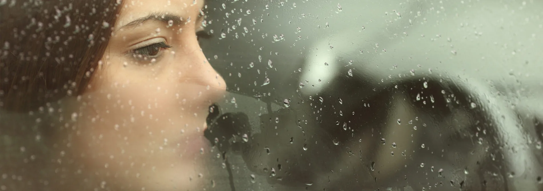 Woman who looks sad looking out window of car